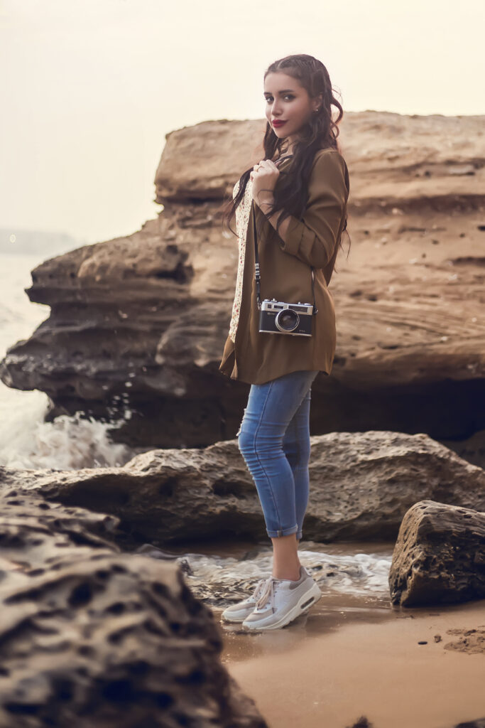 girl is standing at the beach on the stones